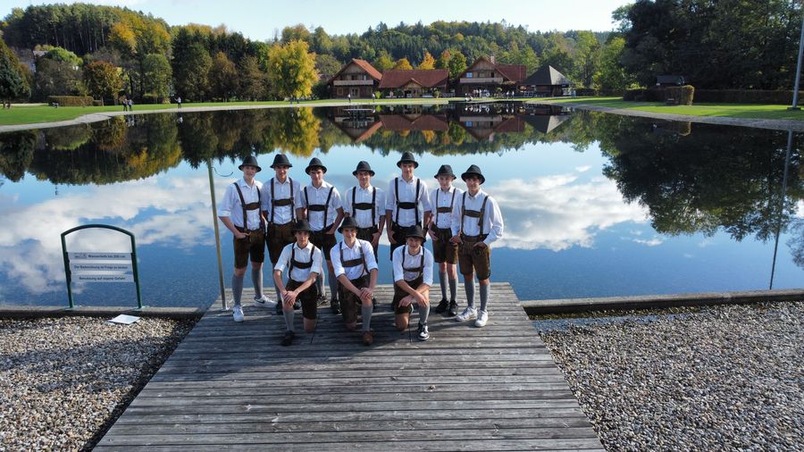 Gruppenfoto der Plattler in Lederhosen auf einem Holzsteg an einem Teich