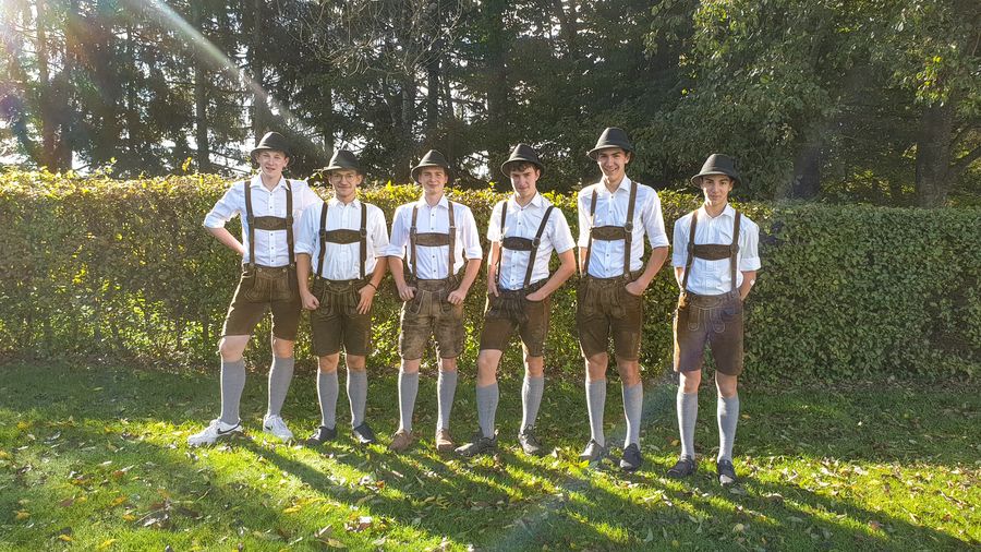 Sechs Plattler in Lederhosen vor einer Hecke